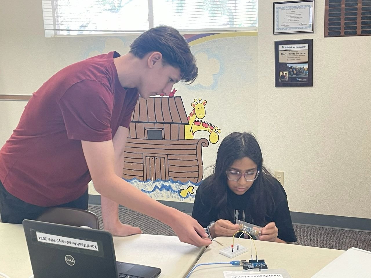 An instructor helps a student work with electronics